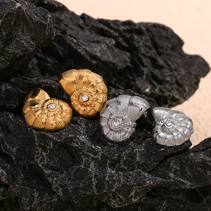 Détail de boucles d'oreilles coquillages dorées et argentées avec cristaux sur roche