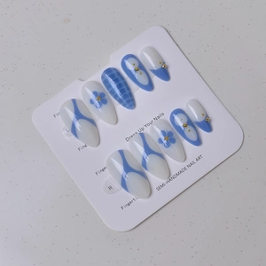 Macro shot of blue and white almond press-on nails with crocodile texture and floral art