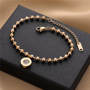 Detail of rose gold bead bracelet with Roman numeral crystal charm on black jewelry box