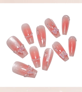 Detailed view of pink blush press-on nails featuring 3D butterfly charms and pearls