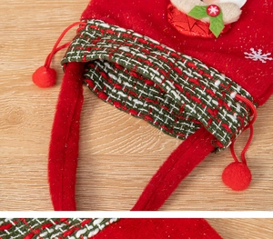 Detail of Christmas felt gift bag with snowflake patterns and red plush pompom drawstrings
