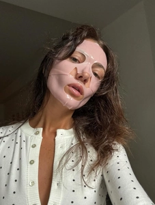 Masque visage rose en gel sur femme en gilet à pois rétro sur fond de mur gris