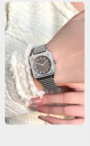 Dettaglio dell'orologio quadrato argento GEDI con quadrante grigio e viti industriali