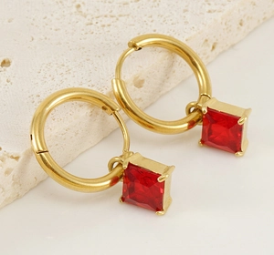 Macro detail of 18K gold stainless steel earrings with square red zircon gemstone