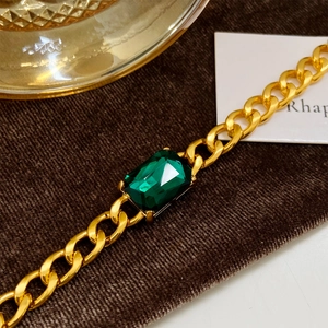 Detail of gold Cuban chain bracelet featuring a large emerald-cut green zircon centerpiece