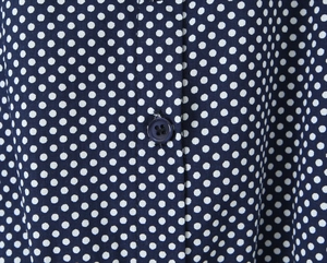 Dettaglio del tessuto blu scuro a pois bianchi con un bottone a quattro fori coordinato