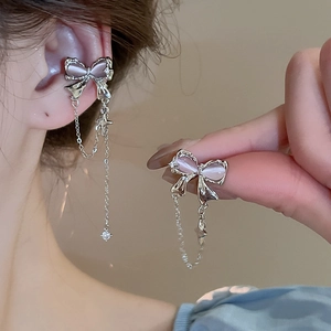 Detail of silver bow tassel earrings with pink cat eye stone and star charms