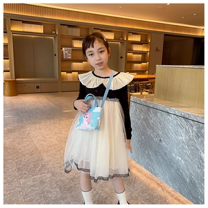 Blue unicorn crossbody bag shown with a black and white dress in an elegant lobby
