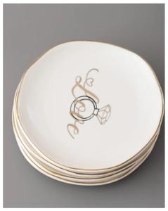 Detail of stacked irregular ceramic jewelry trays with gold Love and ring pattern