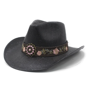 Black straw cowboy hat with floral embroidery and vintage metal ornament on white background