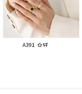 Close-up of gold signet rings with green and clear gemstones on a model's hand