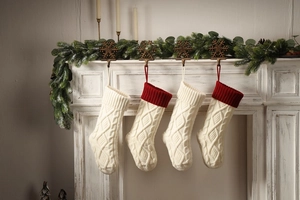 Knitted Christmas stockings in cream and red hanging on a white fireplace mantle