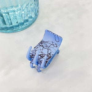 Vue détaillée de la pince à cheveux bleu clair avec texture abstraite noire sur fond blanc