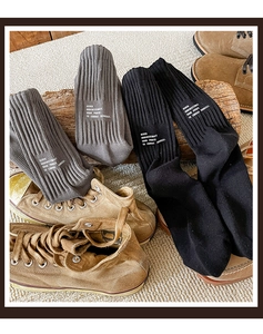 Close-up of cotton crew socks in black and gray with knitted texture and printed text