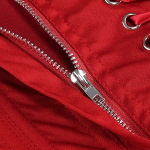 Détail macro d'une fermeture éclair argentée et d'œillets sur un tissu satin rouge