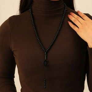 Close-up of long black 99 beads prayer necklace with moon and star pendant on a sweater