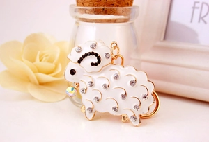 Close-up of cute sheep keychain with white enamel and sparkling rhinestones for handbags