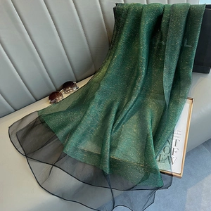 Detail of green silk scarf with gold glitter and black mesh trim on a sofa