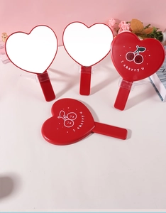 Dettaglio di specchi a mano rossi a cuore con simpatica stampa di ciliegie sul retro.