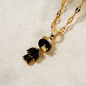 Macro detail of a gold bear pendant with black gemstone on a white satin background