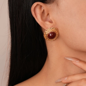 Close-up of vintage gold wheat pattern earrings with a deep red round gemstone insert