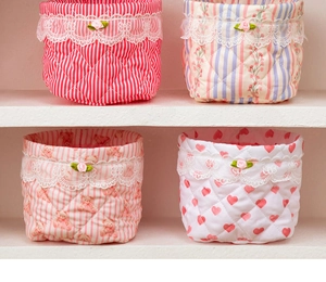 Detailed view of quilted storage baskets with lace edges and pink rose decorations