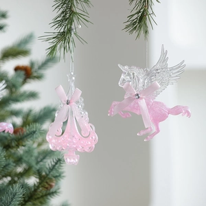 Pink glitter unicorn and Christmas tree ornaments hanging with ribbon on a green branch