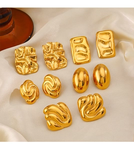 Detail of five pairs of 18K gold plated geometric stainless steel earrings on silk