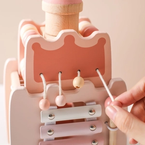Close-up of wooden rocket toy with xylophone keys and crown-shaped bead panel