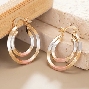 Three-tone double hoop earrings in gold, silver, and rose gold on a natural stone base