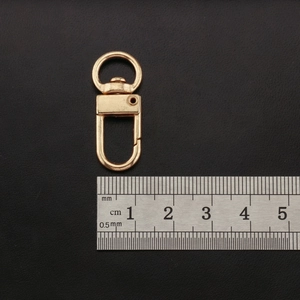 Close-up of golden lobster clasp with D-ring measuring 32mm on size ruler scale