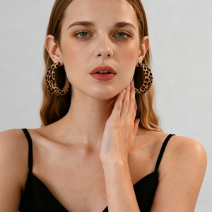 Close-up of leopard print velvet geometric C-shaped earrings worn by a model