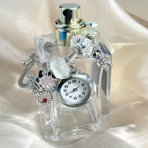 Close-up of silver beaded bracelet watch with Mickey and crown charms on perfume bottle