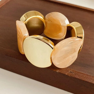 Detail of wide stretch bracelet with gold metal and beige marble resin geometric plates