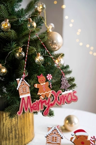 Close-up of wooden Merry Xmas ginger man ornaments hanging on a festive Christmas tree
