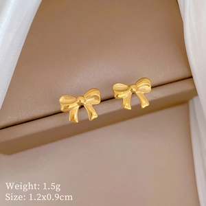 Close-up of golden bow stud earrings showing dimensions 1.2x0.9cm and 1.5g weight