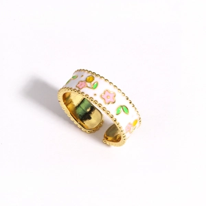 Detailed view of wide open gold ring with colorful enamel flower patterns and green leaves
