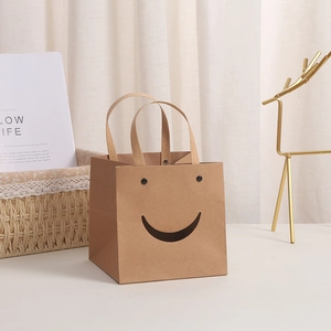 Geschenktüte aus braunem Kraftpapier mit lachendem Gesichtsausschnitt und Tragegriffen