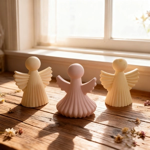 Three minimalist angel wing candle ornaments on wooden table with warm natural light
