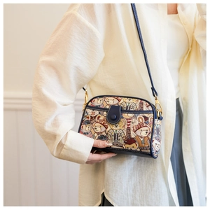 Detail of vintage bear pattern jacquard fabric and navy leather trim on a shoulder bag