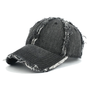 Close-up of distressed charcoal denim baseball cap with frayed edges and retro washing texture