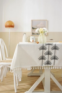 Detailed embroidery of black floral pattern and white tassels on beige tablecloth