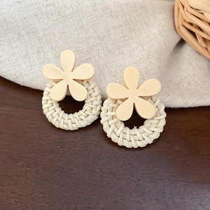 Detailed close-up of handmade wicker hoop earrings with cream yellow floral acrylic studs