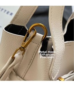Close-up of white lychee leather texture with brushed gold metal hook and fine stitching
