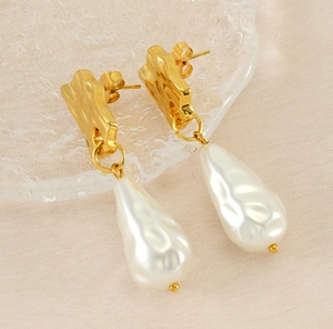 Détail de boucles d'oreilles vintage françaises avec perle goutte et métal martelé