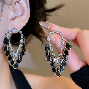 Detail of silver drop earrings with black stones and white zircons worn on ear