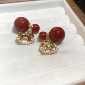 Detail of 18K gold plated rocking horse earrings with sparkling zircons and red beads