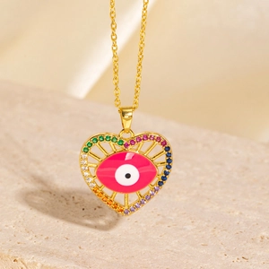 Close-up of heart-shaped evil eye pendant with colorful gemstones on a gold chain