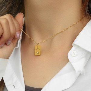 Close-up of golden sun tarot card pendant necklace featuring celestial moon and star relief