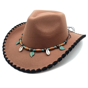Detailed shot of brown cowboy hat featuring ethnic beads, shells and bronze leaf pendant